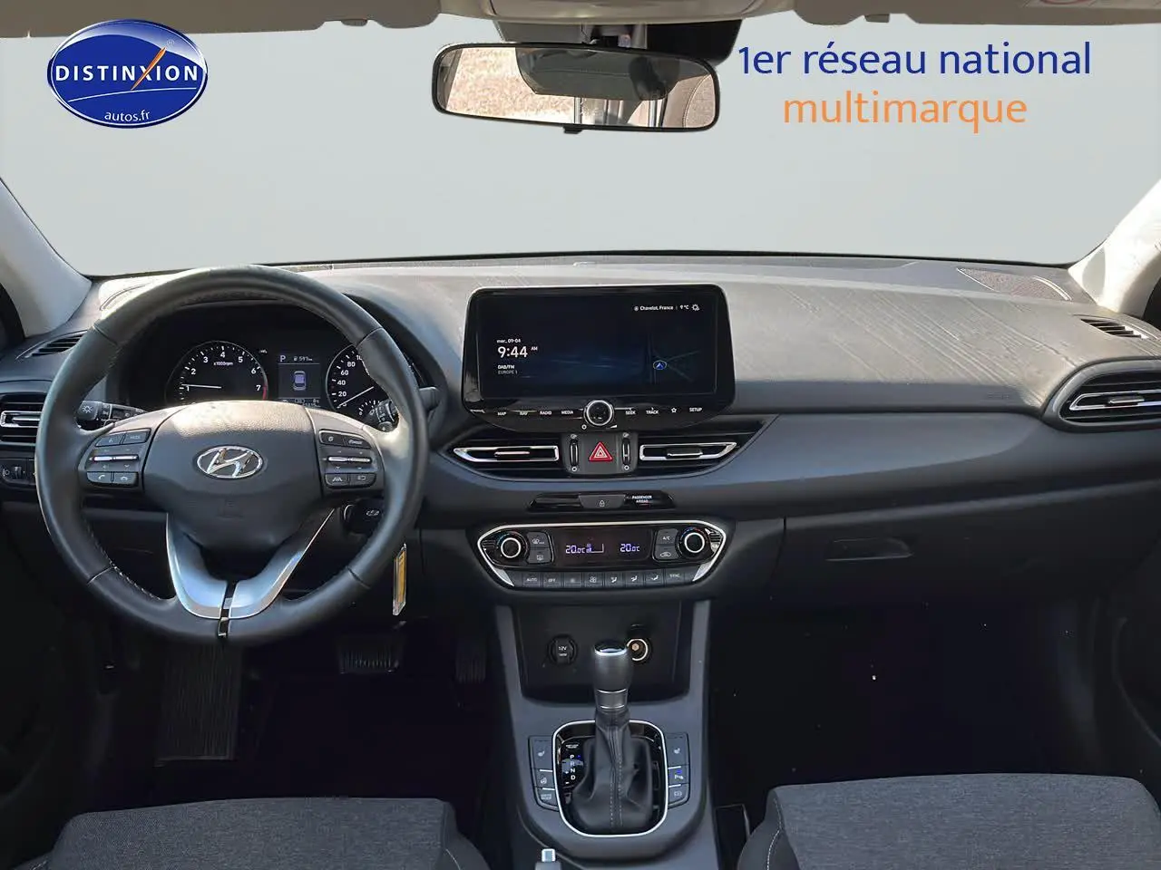 Intérieur de la Hyundai i30 2024 en gris, vue frontale du tableau de bord avec écran tactile et volant cuir multifonction.