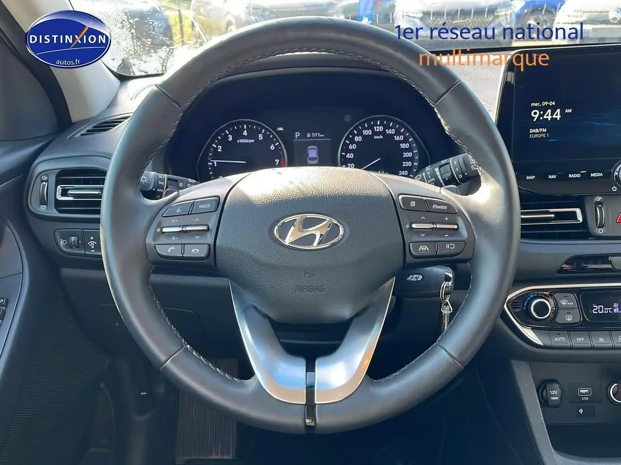 Vue centrée sur le volant cuir multifonction d'une Hyundai i30 gris argent 2024 avec tableau de bord et écran tactile visible.