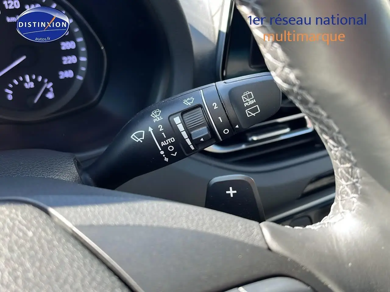 Gros plan sur la commande d'essuie-glace et palette de changement de vitesse du volant cuir d'une Hyundai i30 gris argent 2024.