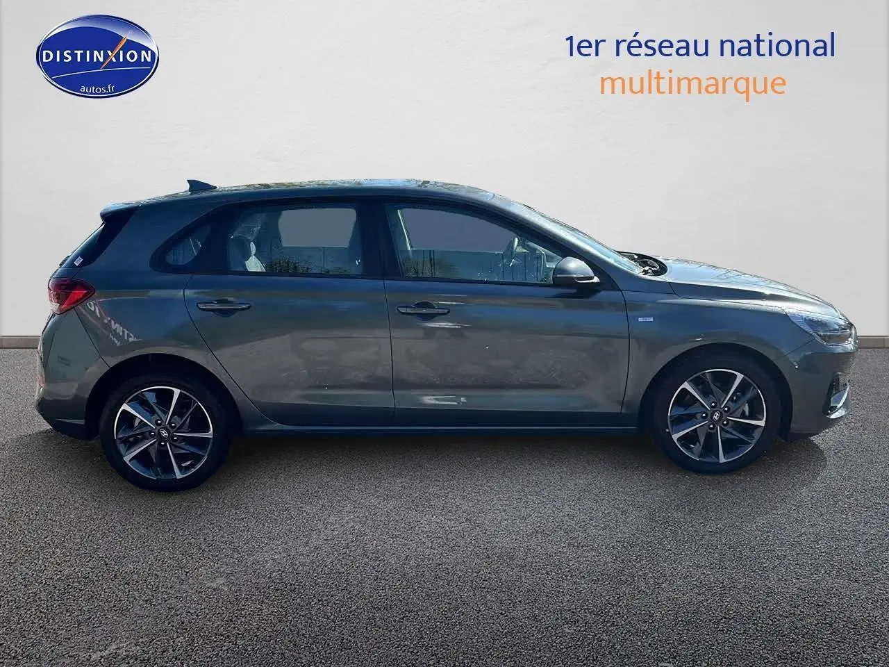 Profil côté gauche d'une Hyundai i30 gris argent 2024 avec jantes alliage et vitres teintées sur fond neutre.