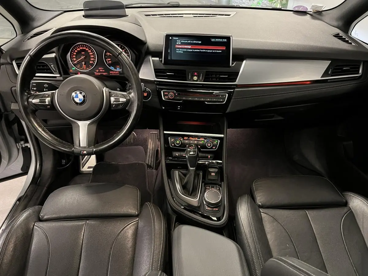 Vue intérieure avant de la BMW Série 2 225xe M Sport avec tableau de bord noir et console centrale moderne.