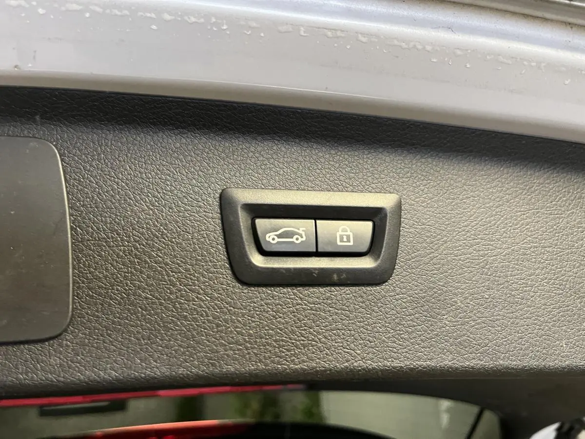 Gros plan sur les boutons d'ouverture et de verrouillage du hayon du BMW Série 2 225xe gris, vue intérieure du coffre.