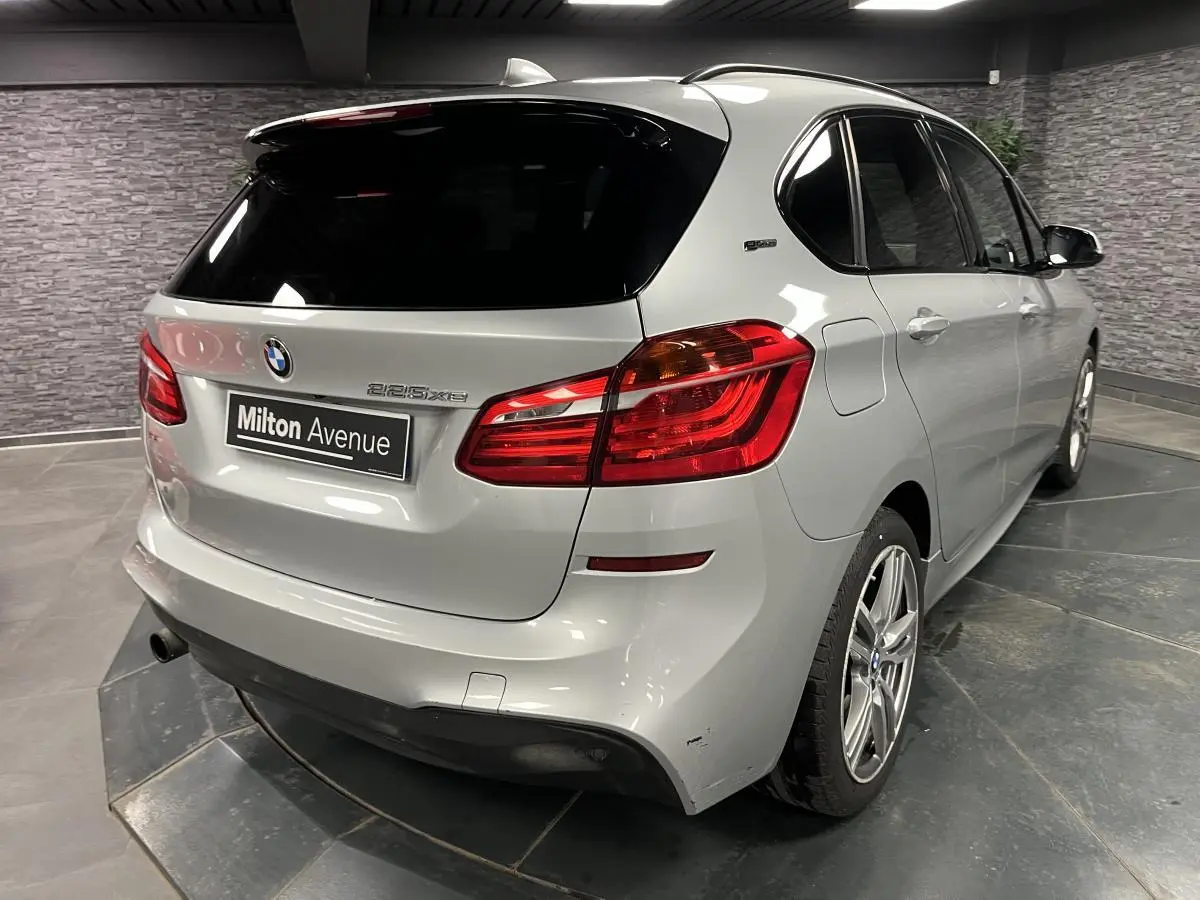 BMW Série 2 225xe Active Tourer gris vue 3/4 arrière droit avec feux arrière rouges et jantes alliage 18 pouces