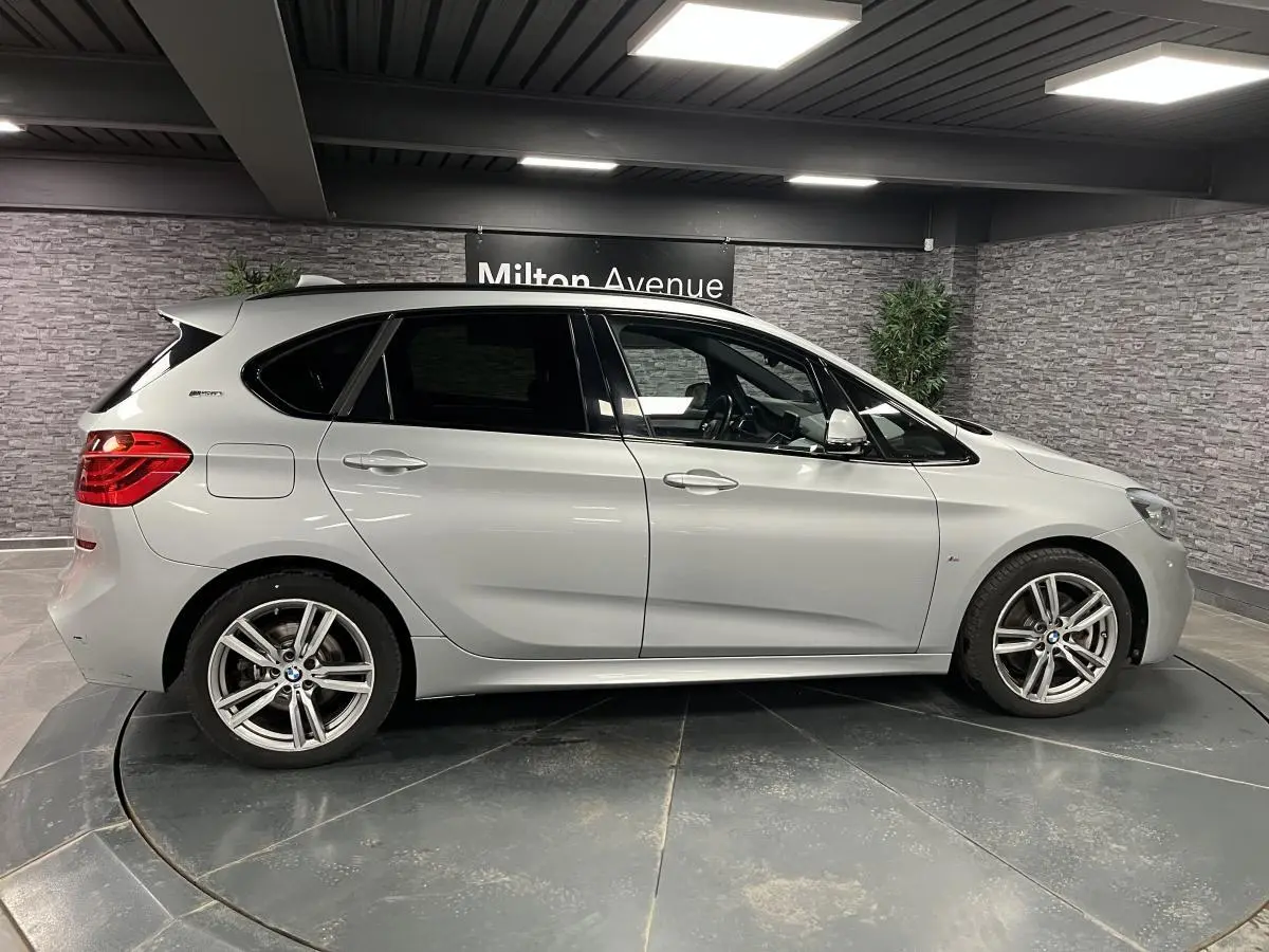 BMW Série 2 225xe Active Tourer gris vue de profil côté gauche en intérieur avec jantes alliage et vitres teintées.