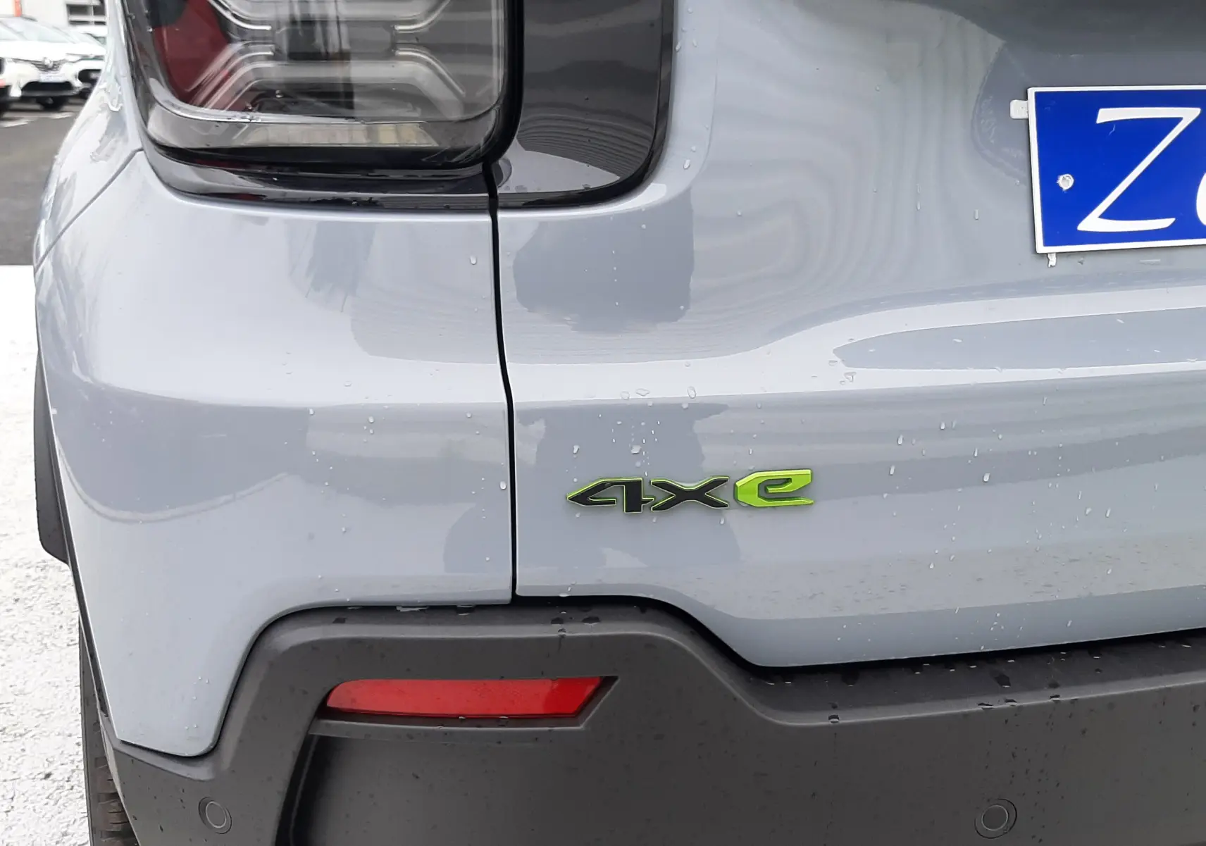 Gros plan sur l'arrière gauche gris Storm du Jeep Avenger 2025 avec logo 4xe vert et feux noirs.