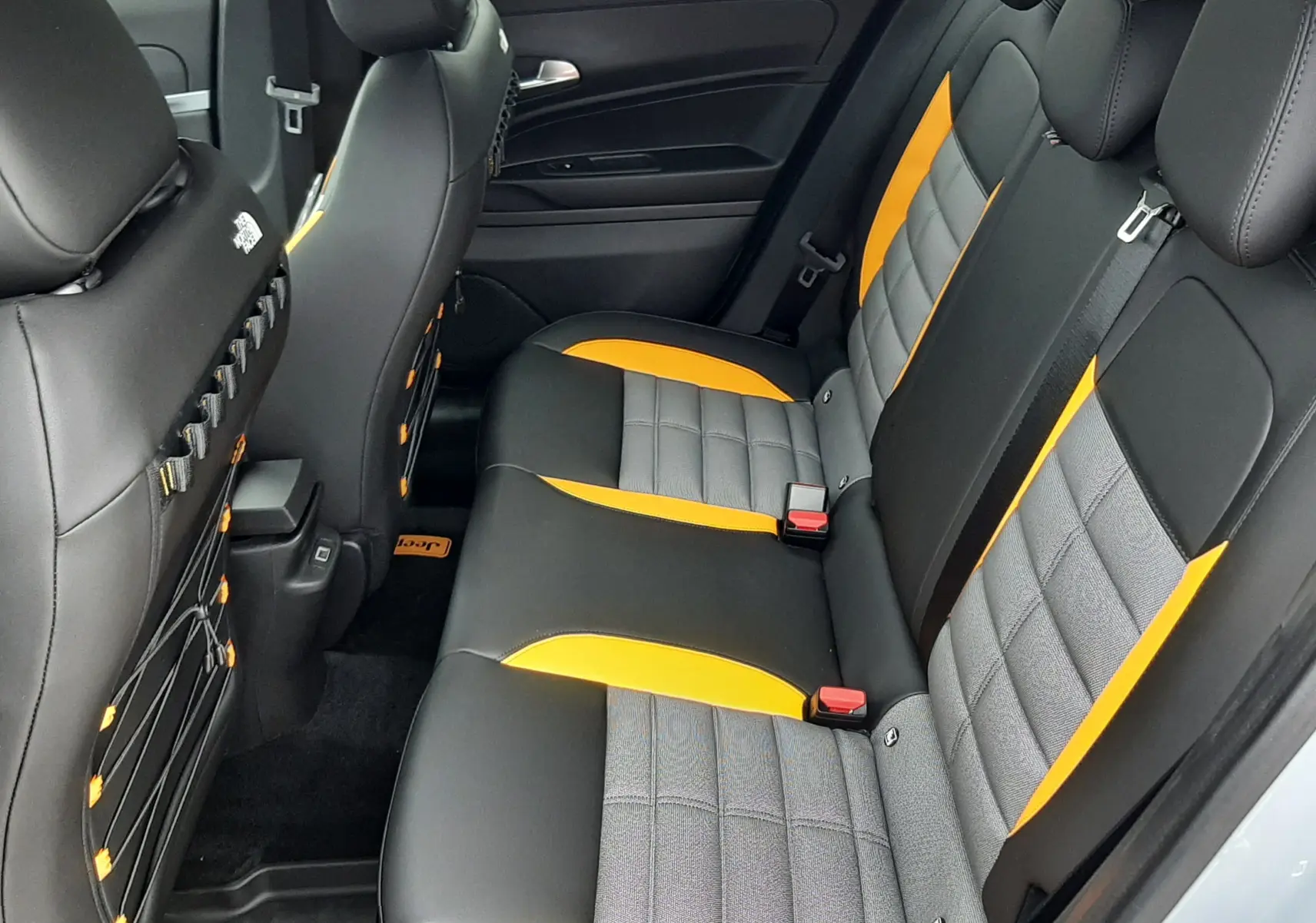 Vue intérieure arrière du Jeep Avenger 2025, sièges noirs avec inserts gris et touches jaunes contrastantes.