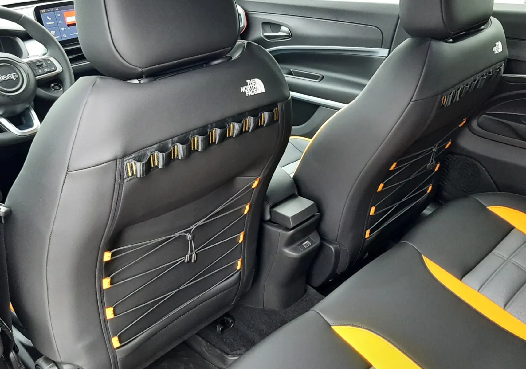 Vue intérieure arrière des sièges noirs avec logo The North Face et surpiqûres orange du Jeep Avenger 2025.