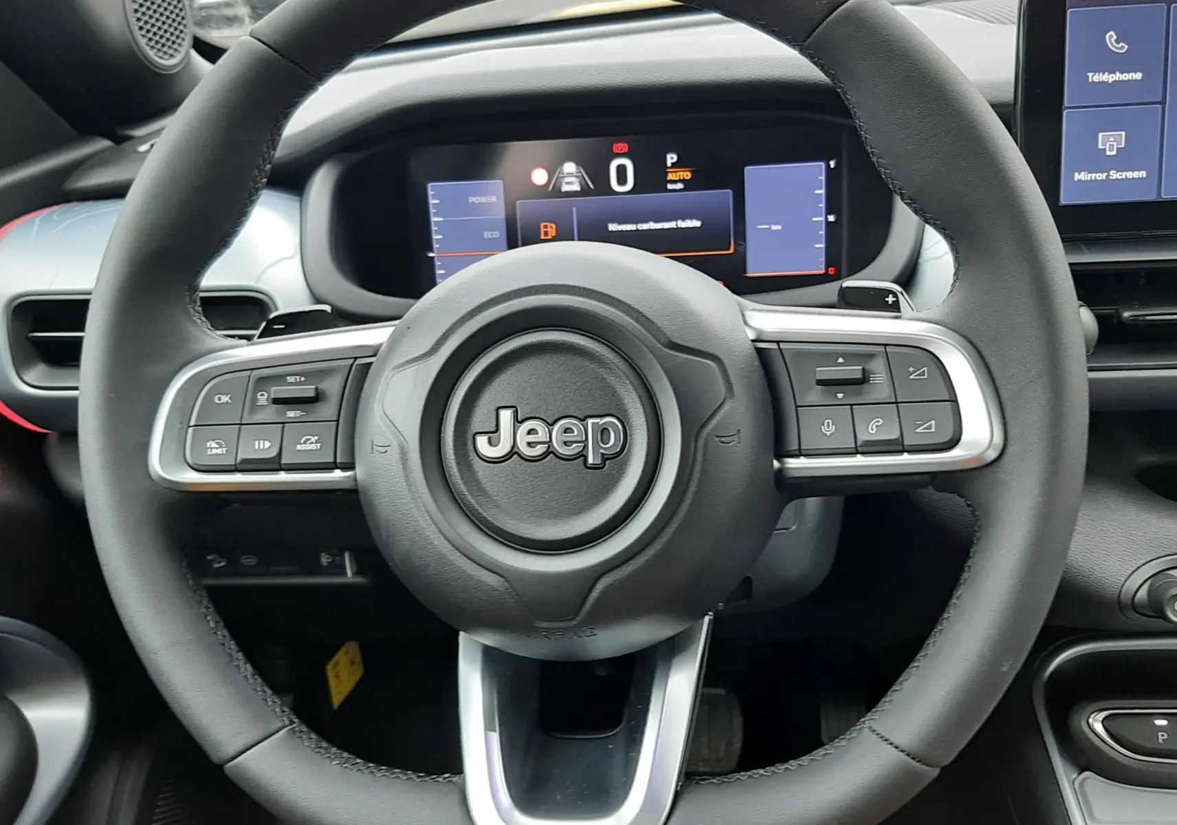 Vue frontale du volant noir de la Jeep Avenger 2025 avec tableau de bord numérique et écran central visible.