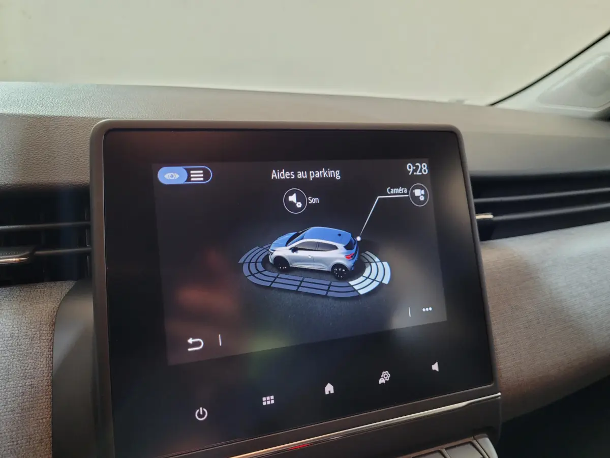 Écran tactile central montrant l'aide au parking avec illustration 3D d'une Renault Clio gris clair vue de dessus.