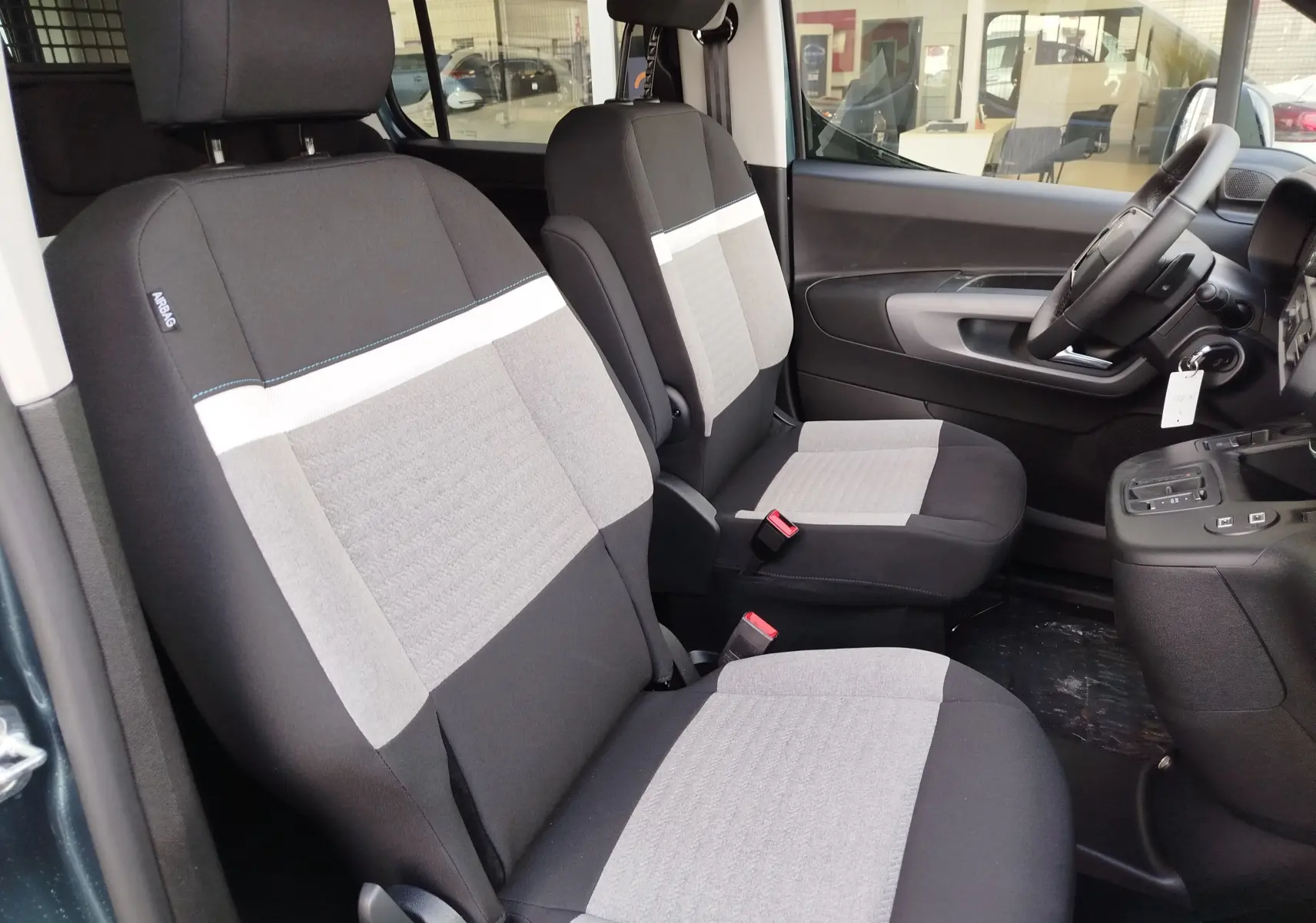 Vue intérieure côté gauche montrant les sièges avant gris et noirs du Citroën Berlingo 2025 Bleu Kiarma.