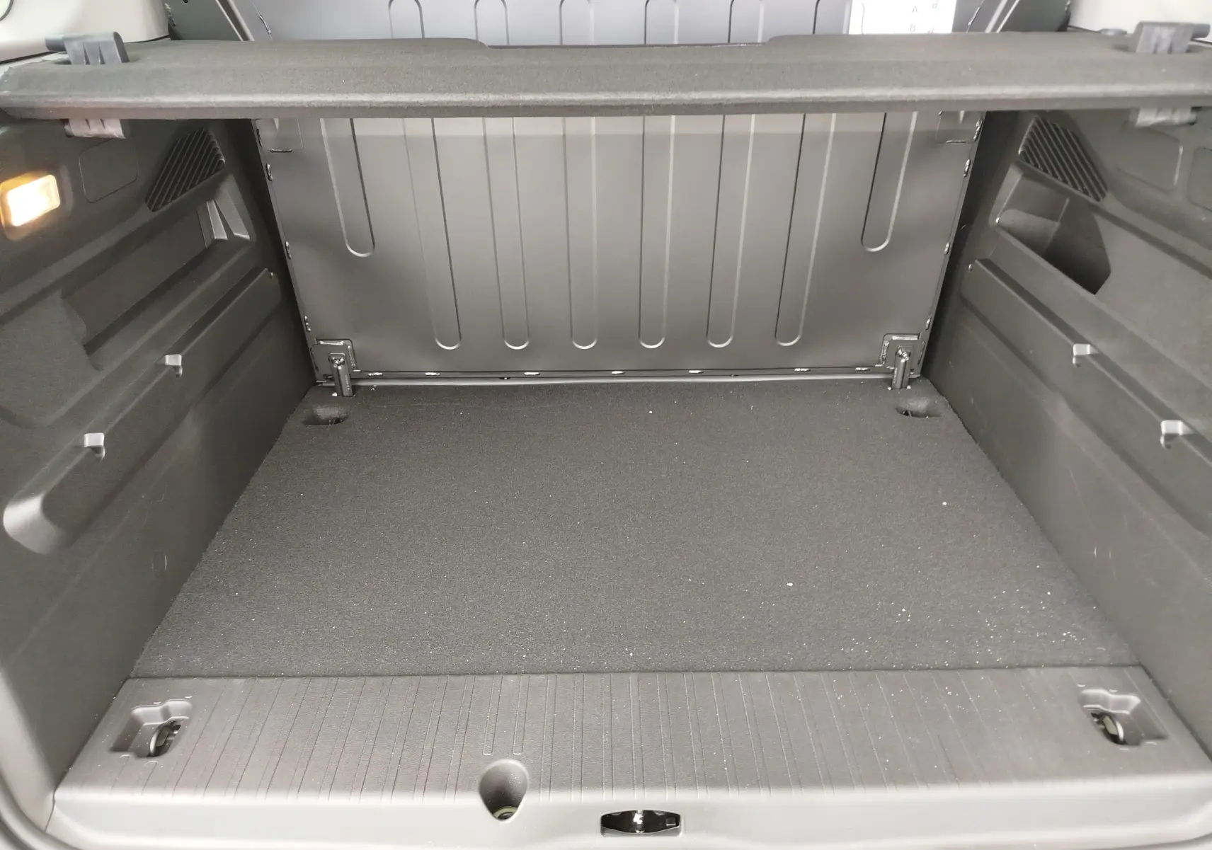 Coffre spacieux vu de l'arrière du Citroën Berlingo 2025 bleu Kiarma, avec revêtement noir et éclairage intérieur.