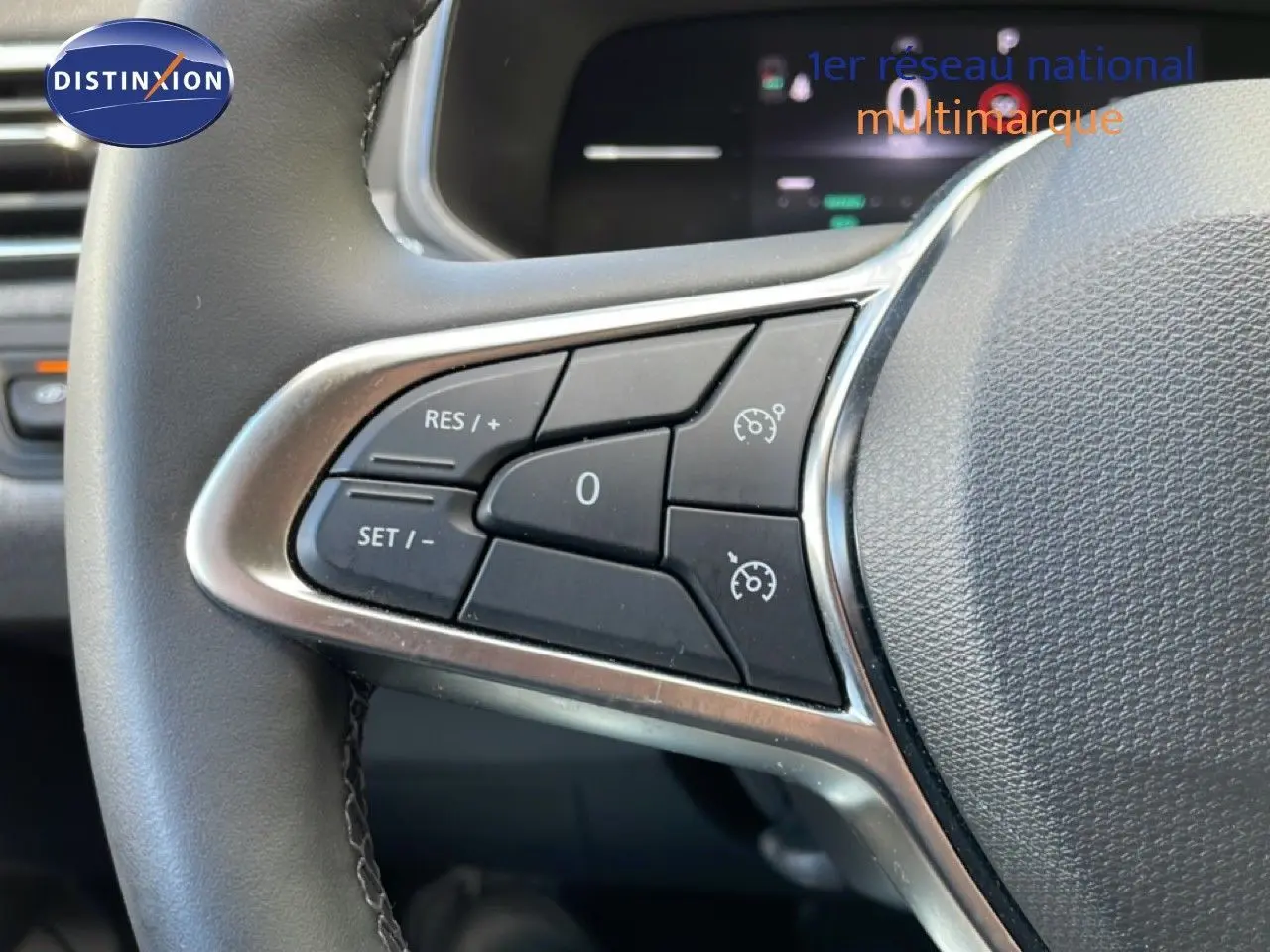 Gros plan sur les commandes de régulateur de vitesse au volant de la Renault Clio gris schiste métal, intérieur moderne.