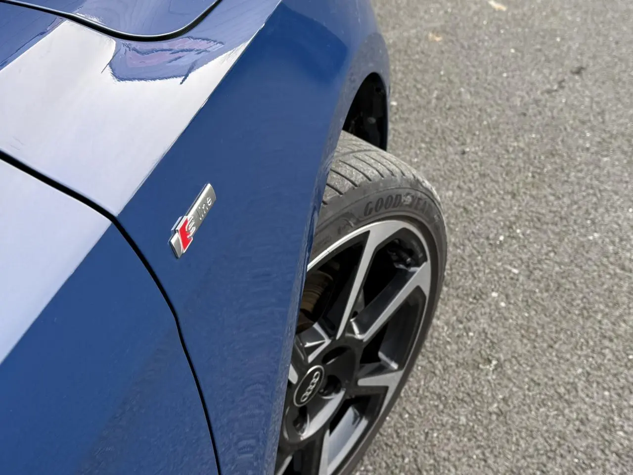 Gros plan sur l'aile avant gauche bleu Ascari d'une Audi A1 Sportback 30 TFSI avec badge S line et jante noire 18 pouces.