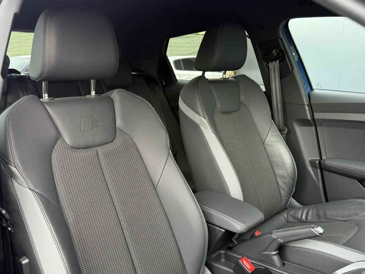 Gros plan sur les sièges avant sport cuir/tissu noirs avec logo S line dans l'Audi A1 Sportback bleu Ascari 2023.