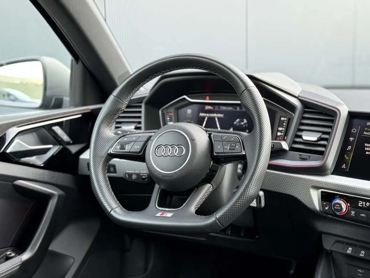 Volant sport multifonctions en cuir perforé de l'Audi A1 Sportback 30 TFSI 2023, avec tableau de bord numérique et détails noirs.