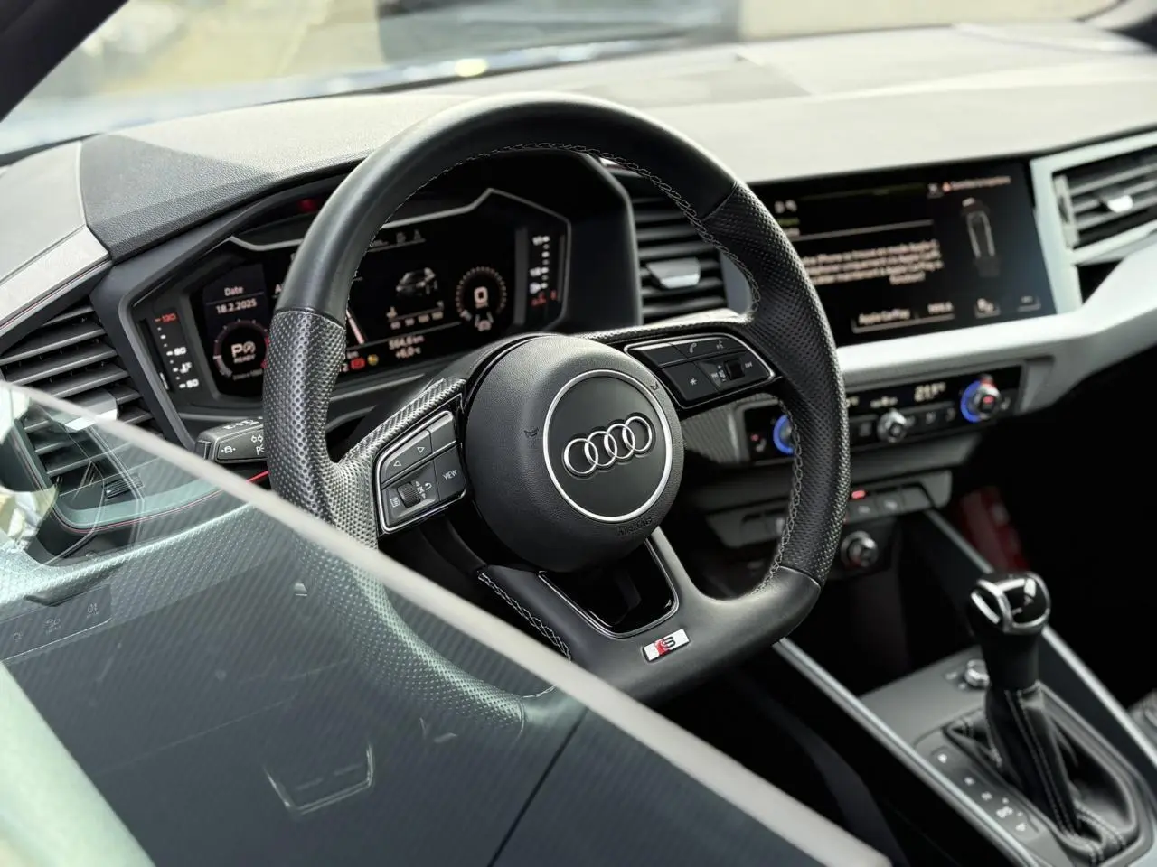 Vue rapprochée du volant sport multifonctions cuir de l'Audi A1 Sportback 30 TFSI 110 S-Tronic Competition, tableau de bord digital visible.