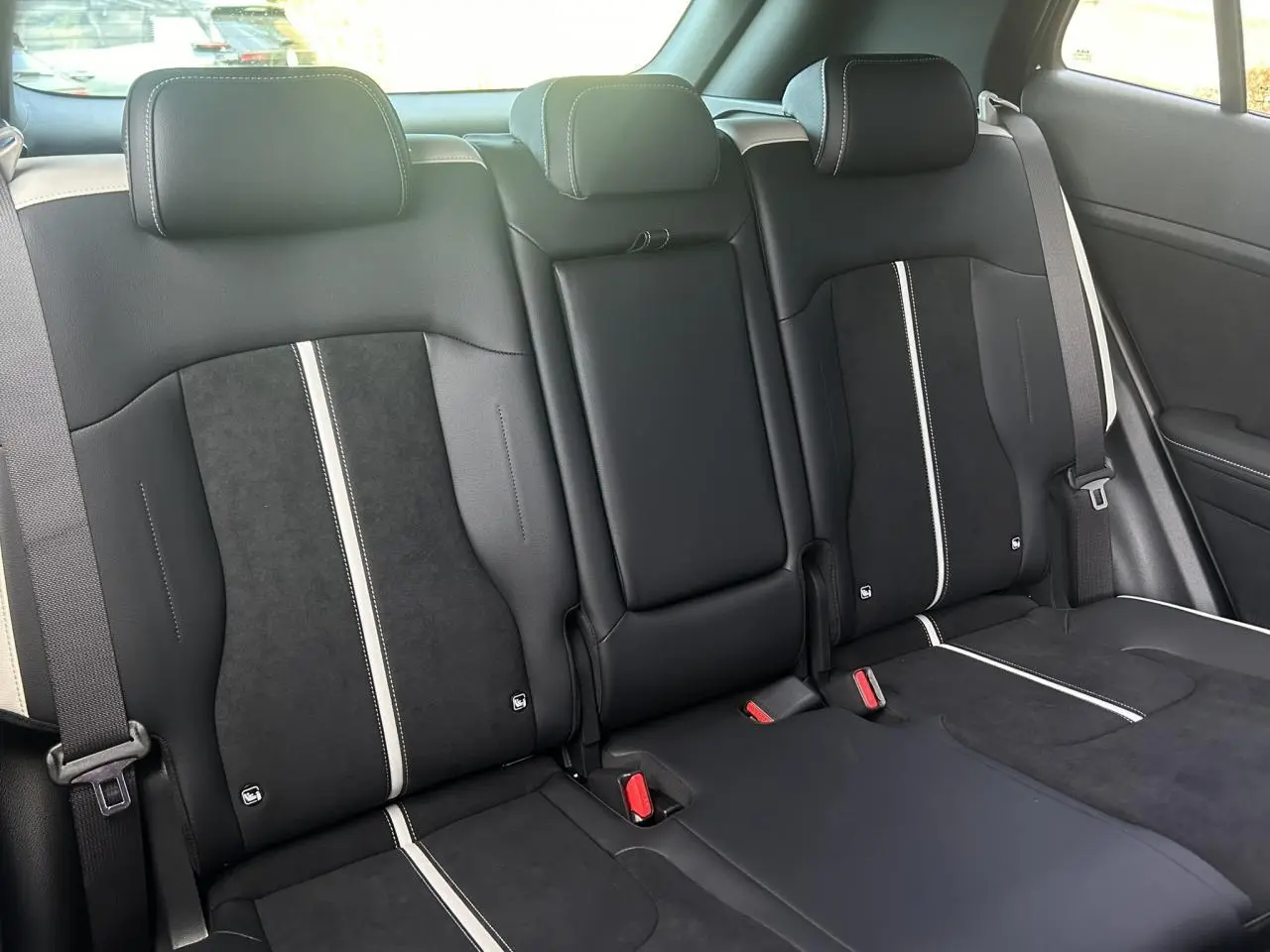 Vue intérieure des sièges arrière bi-ton noir et gris du Kia Sportage 2026 GT-line avec ceintures et appuie-têtes intégrés.