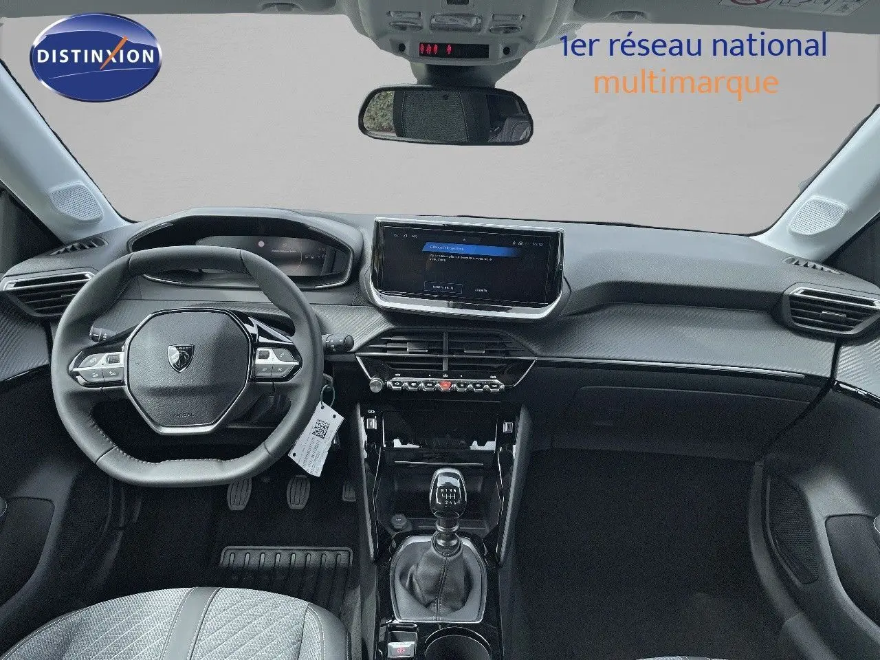 Vue intérieure frontale du tableau de bord et volant de la Peugeot 208 jaune Agueda Metal, avec boîte manuelle visible.