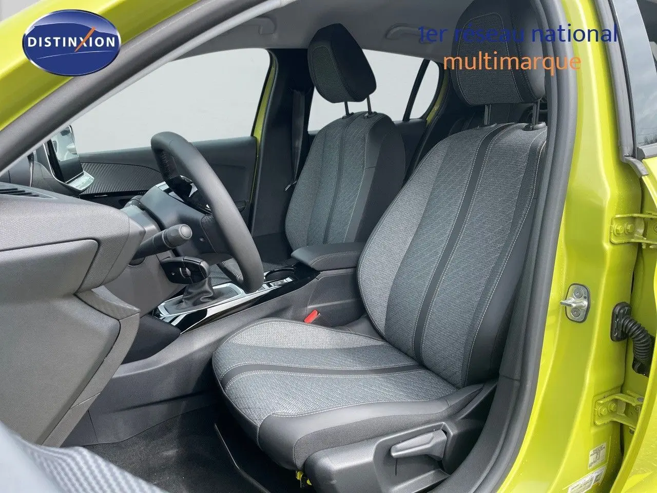 Vue intérieure côté conducteur d'une Peugeot 208 jaune Agueda Metal, sièges tissu gris et noir, volant et console visibles.