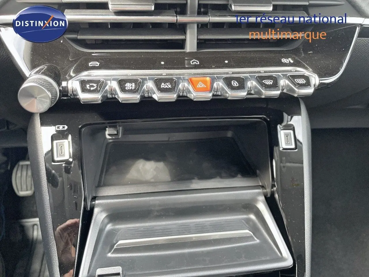 Vue rapprochée de la console centrale noire du Peugeot 208 2025 avec boutons de commande et rangement ouvert.