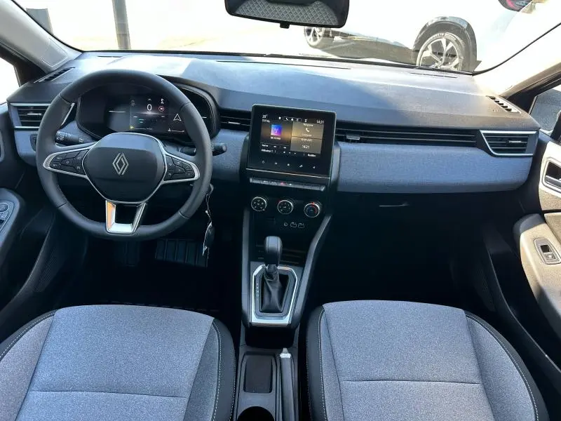 Vue intérieure avant de la Renault Clio 2025 gris Rafale, tableau de bord avec écran tactile et volant multifonction.