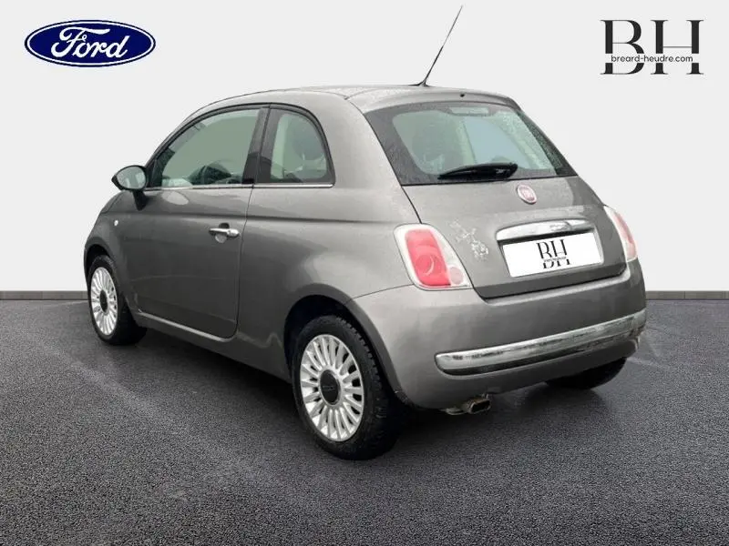 Vue 3/4 arrière droite d'une FIAT 500 marron métal avec jantes alu et toit ouvrant électrique visible.