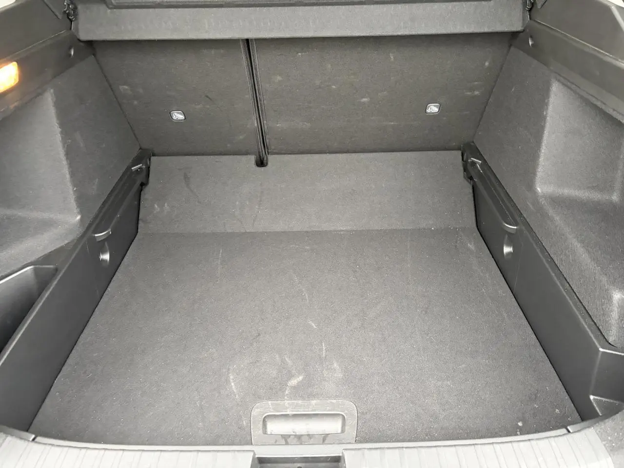 Vue plongeante sur le coffre spacieux et plat du Renault Arkana 2025, revêtement intérieur gris foncé.