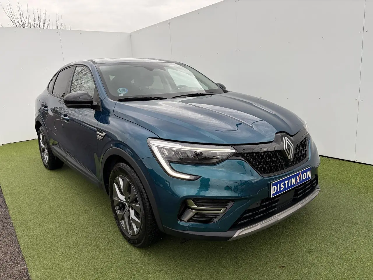 Renault Arkana bleu Zanzibar en 3/4 avant droit, avec jantes alliage et signature lumineuse LED distinctive.