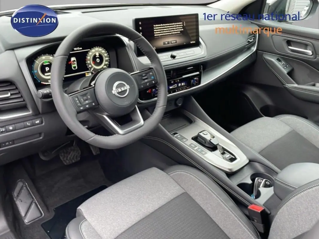 Vue intérieure côté conducteur du Nissan Qashqai 1.5 E-POWER 2025, montrant le volant cuir multifonctions et l'écran tactile central.