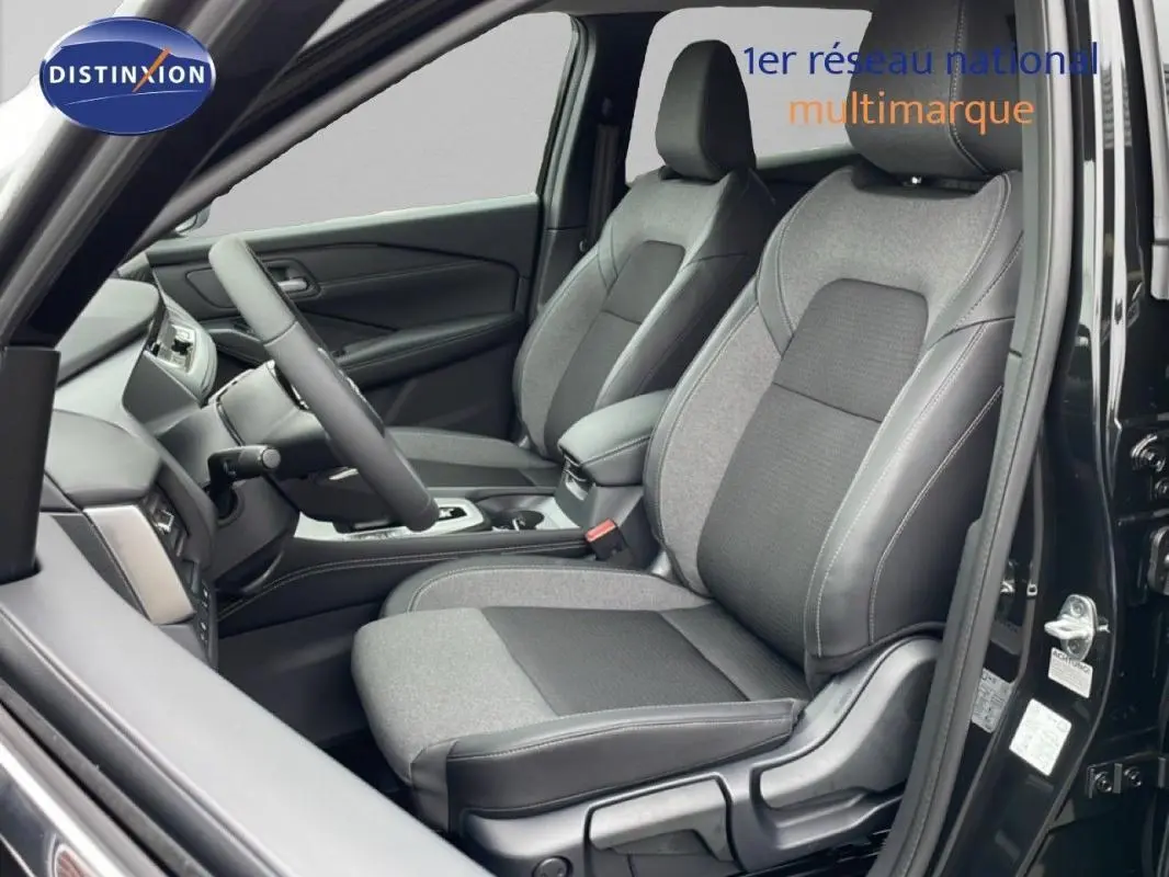 Intérieur du Nissan Qashqai noir 2025 vu côté conducteur, sièges tissu et cuir gris avec volant multifonctions.