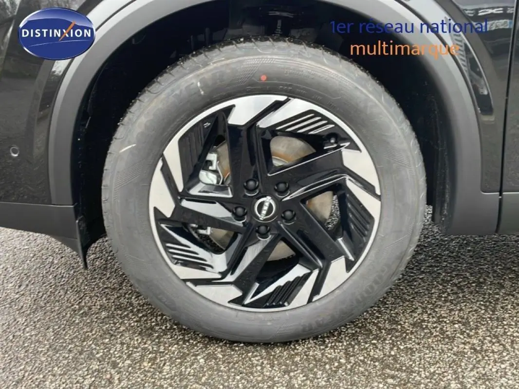 Gros plan sur la jante aluminium noire et argentée du côté gauche d’un Nissan Qashqai noir 2025.
