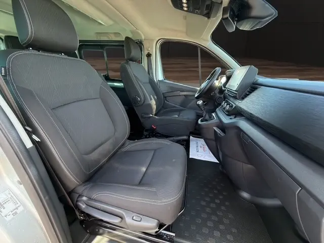 Vue intérieure côté droit du Nissan Primastar gris clair 2025, montrant sièges avant, tableau de bord et écran tactile central.