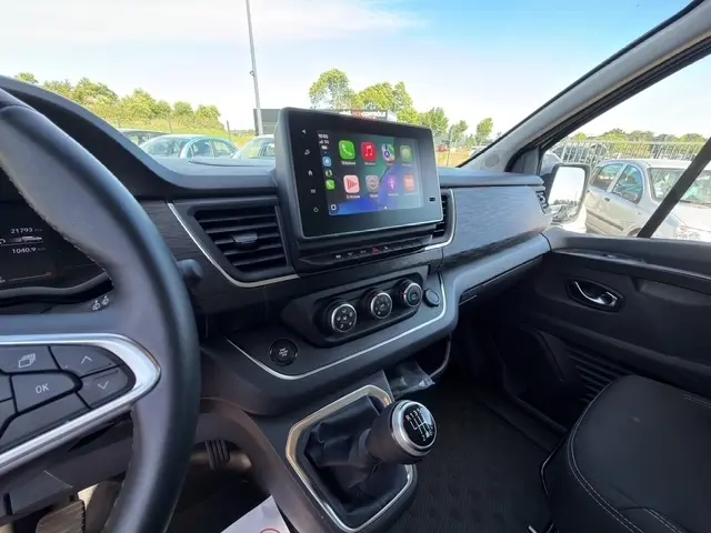 Vue intérieure côté conducteur du tableau de bord et console centrale du Nissan Primastar gris clair avec écran tactile et levier de vitesses manuel.
