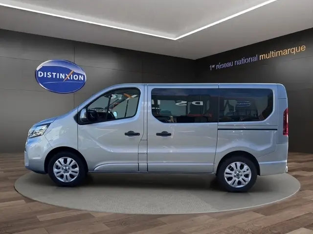 Vue latérale droite d'un Nissan Primastar gris clair, fourgon 8 places avec portes latérales et jantes acier.