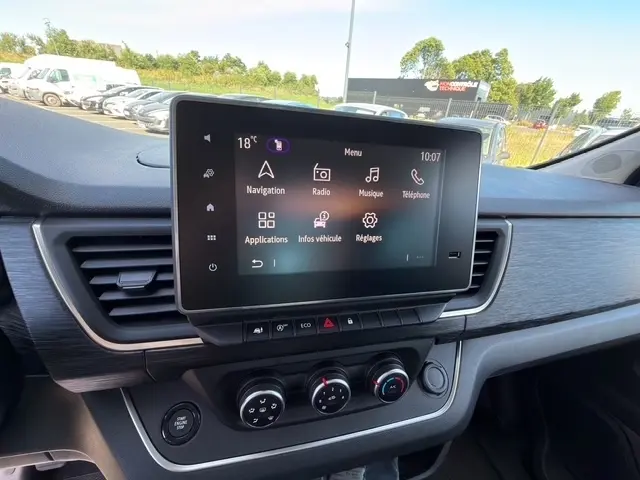 Vue intérieure du tableau de bord du Nissan Primastar 2025 gris clair, avec écran tactile central et commandes climatisation.