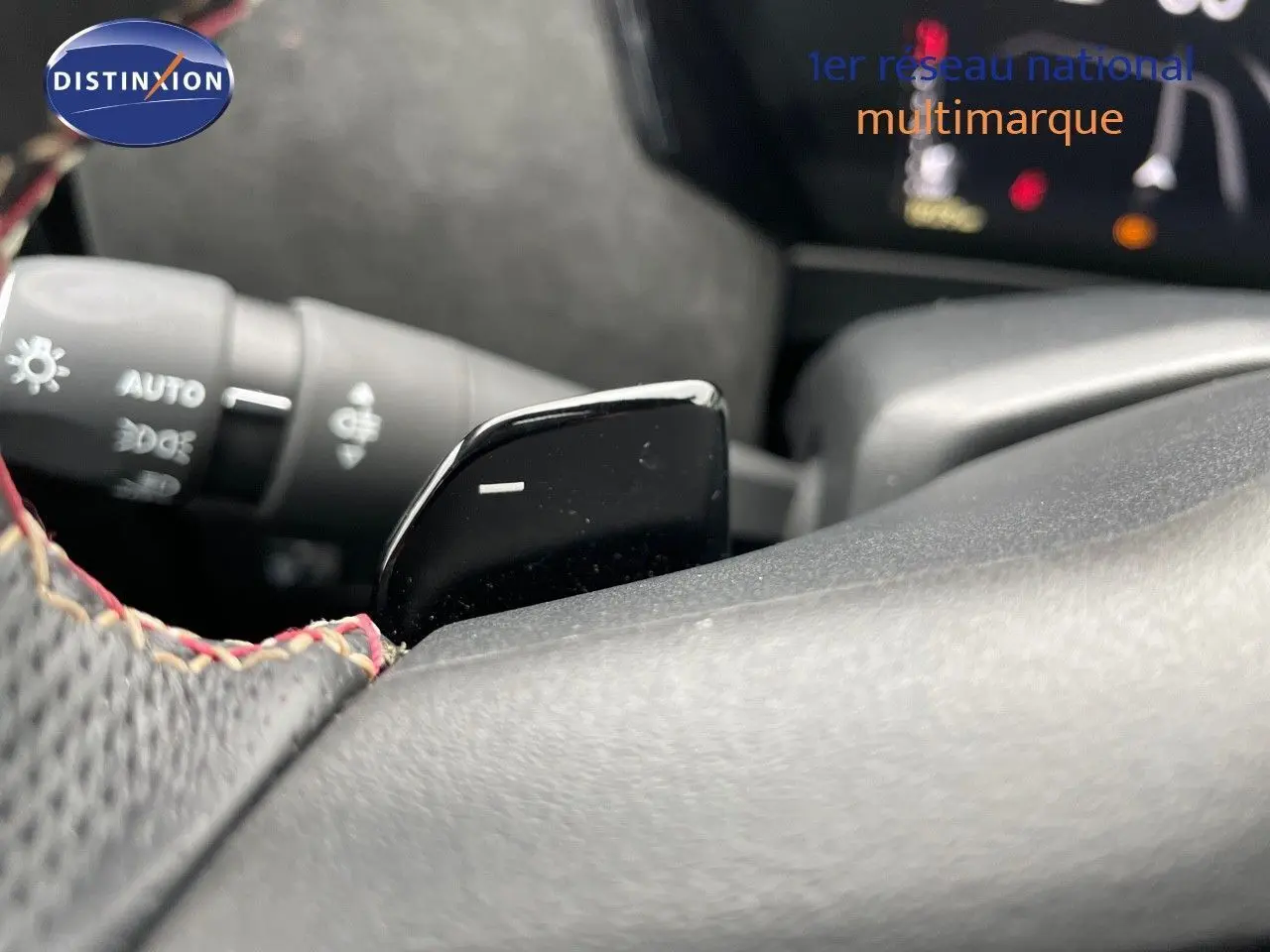 Gros plan sur la palette de changement de vitesse noire côté droit du volant perforé avec surpiqûres rouges du DS4 2024.