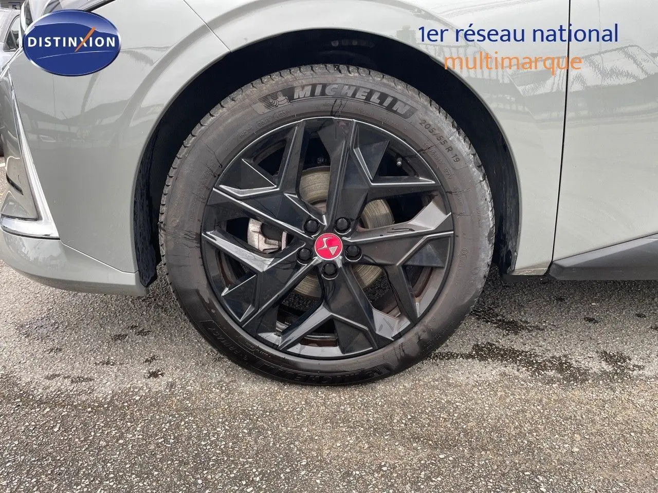 Gros plan sur la roue avant gauche d'une DS4 2024 gris laqué métal avec jante noire au design géométrique.