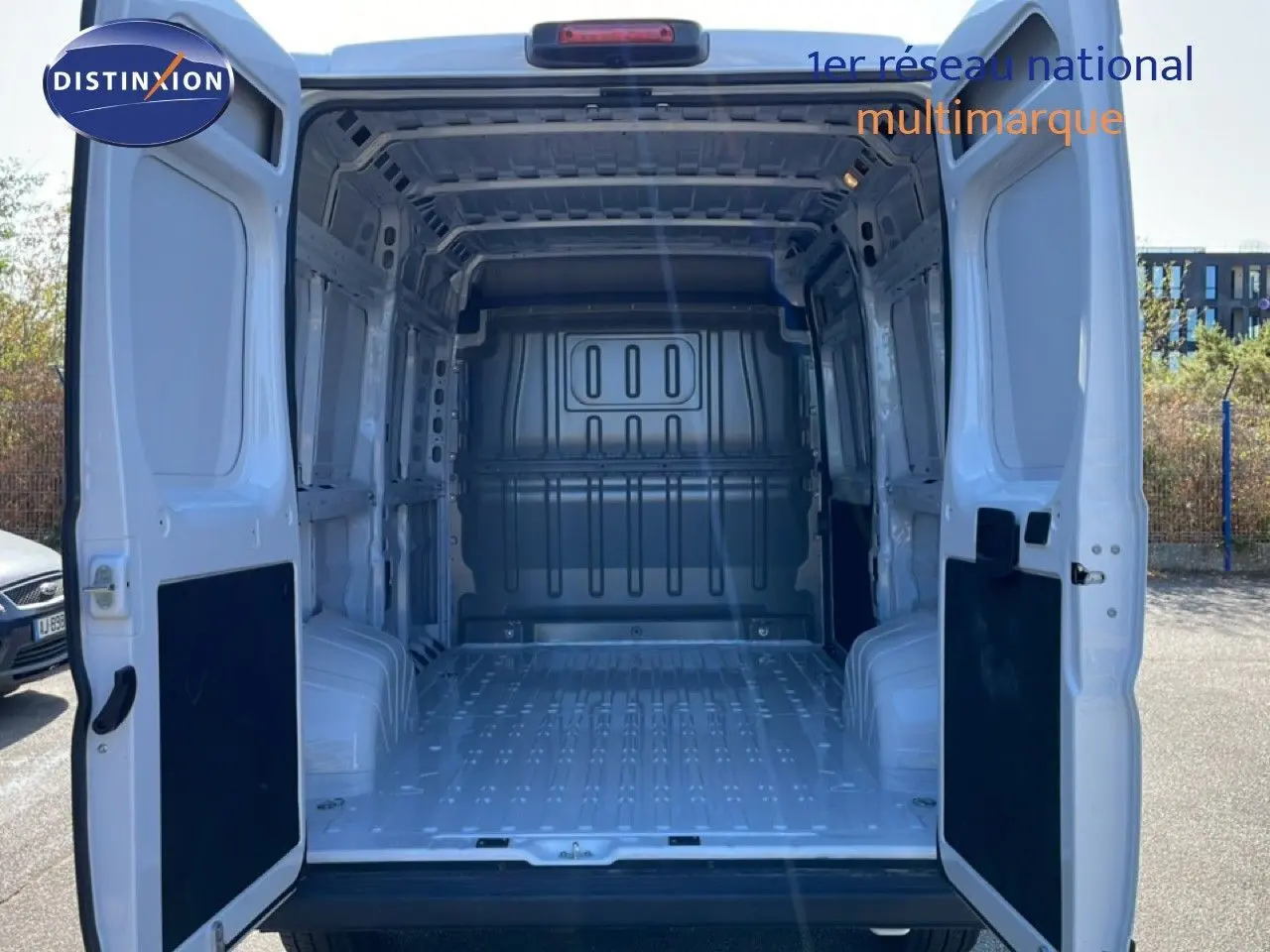 Vue arrière des portes ouvertes du Peugeot Boxer Fourgon blanc banquise, montrant l’espace de chargement vide et métallique.