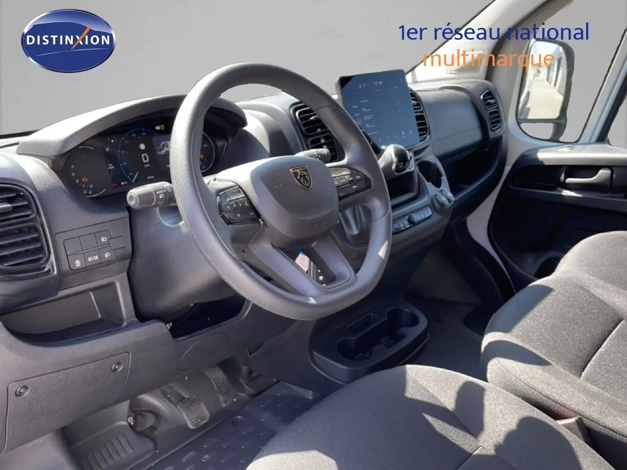 Vue intérieure côté conducteur du Peugeot Boxer Fourgon 2025, tableau de bord noir avec écran tactile central et volant multifonction.