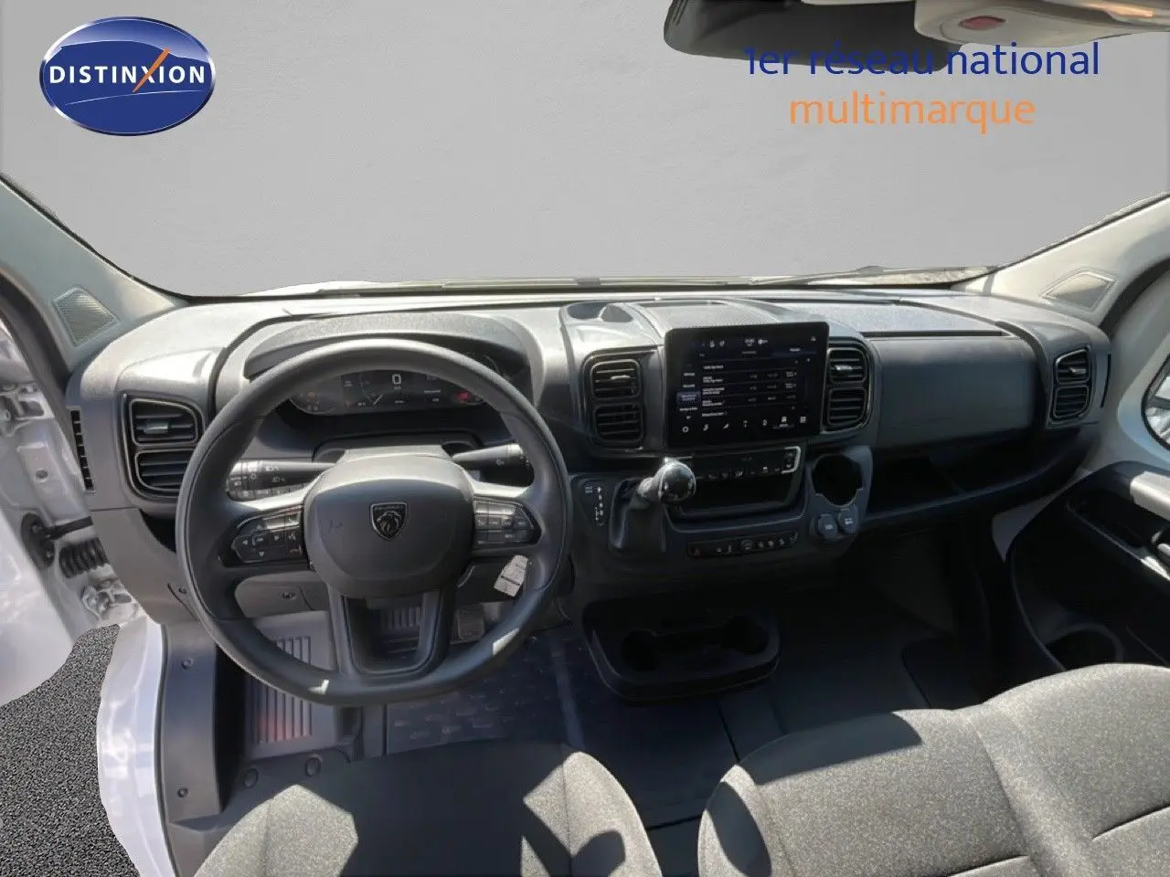 Vue intérieure avant du Peugeot Boxer Fourgon blanc banquise, montrant le volant, tableau de bord et écran tactile central.