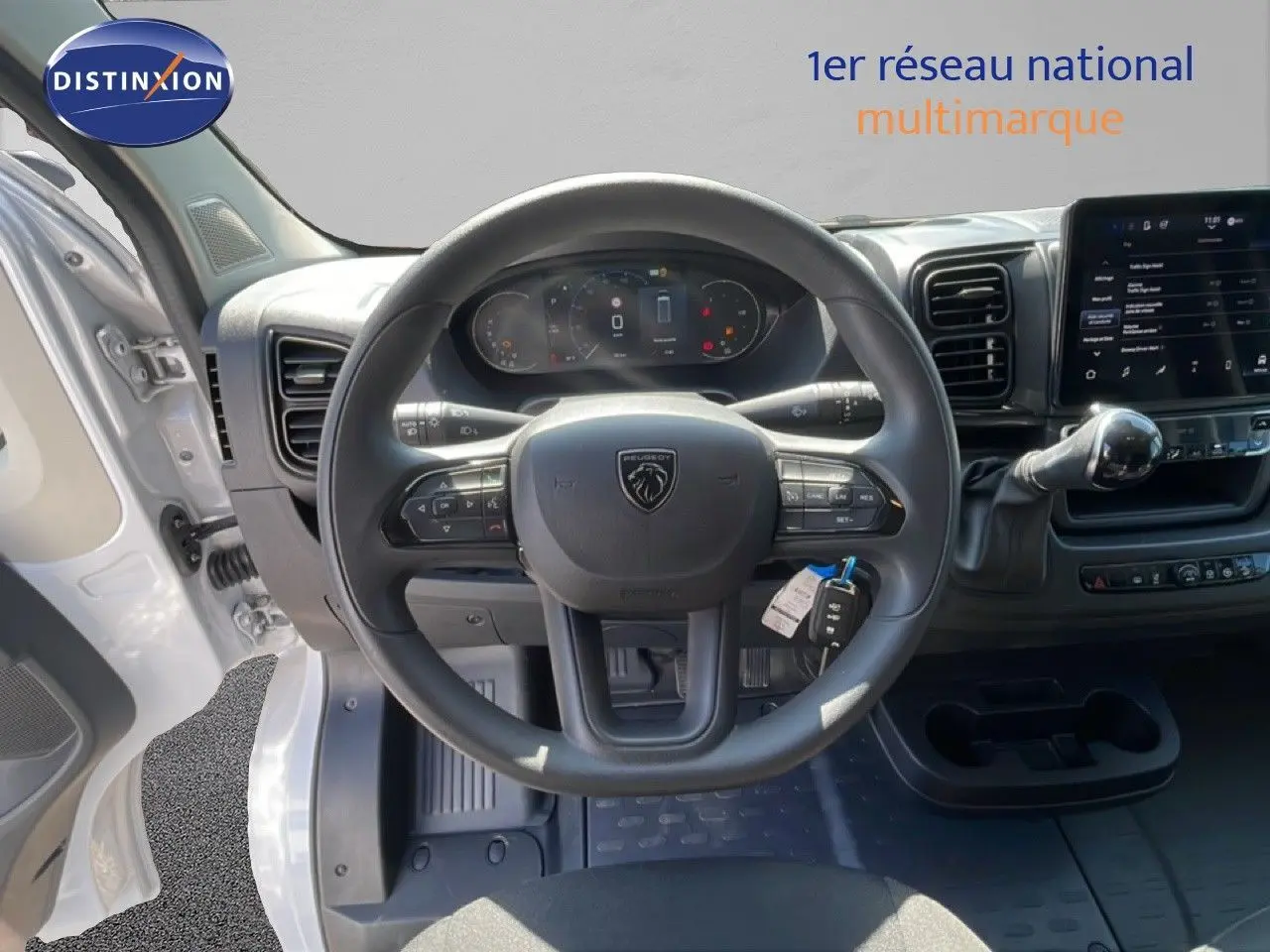 Vue intérieure centrée sur le volant Peugeot d'un Boxer Fourgon blanc banquise avec tableau de bord digital et écran tactile.