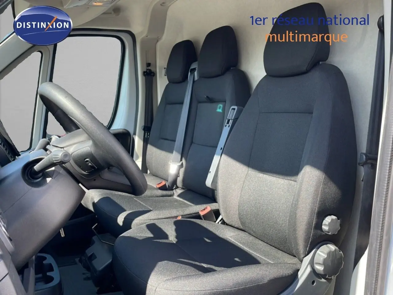 Vue intérieure côté conducteur du Peugeot Boxer Fourgon 2025, montrant les sièges noirs et le volant à gauche.