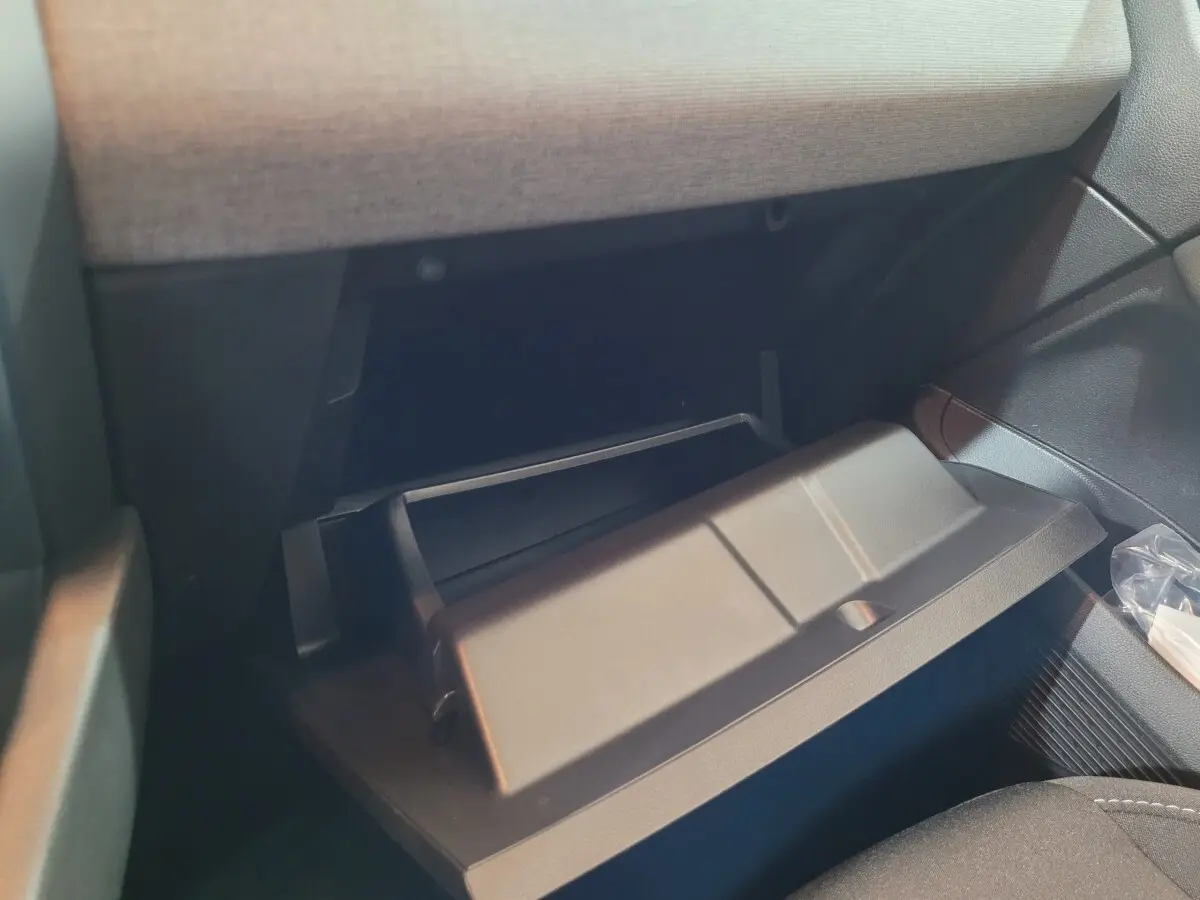 Gros plan sur la boîte à gants ouverte côté passager de la Renault Clio gris foncé, intérieur tissu et plastique.