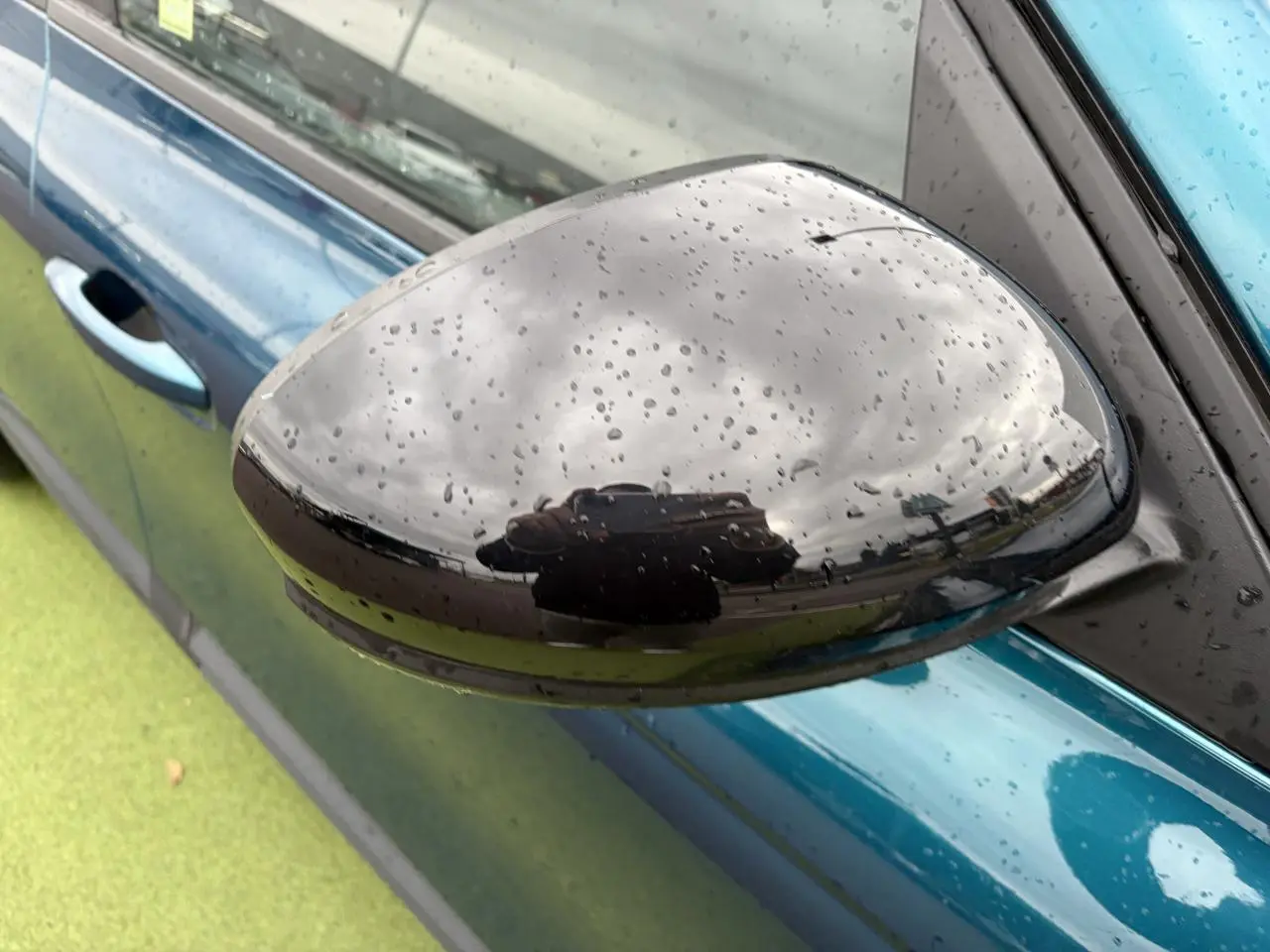Rétroviseur droit noir brillant avec gouttes d'eau sur carrosserie Bleu Zanzibar d'une Renault Arkana 2025.