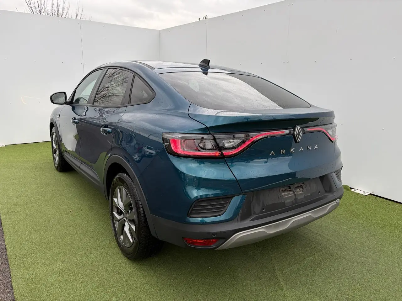 Vue 3/4 arrière droite d’un Renault Arkana bleu Zanzibar métallisé avec feux arrière LED et vitres surteintées.