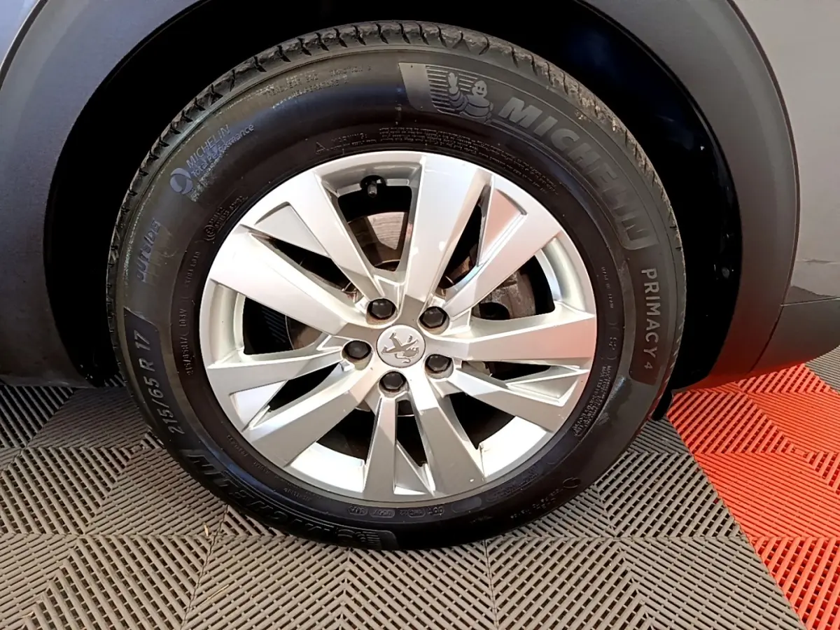 Gros plan sur la roue avant droite d’un Peugeot 5008 gris clair, jante alliage et pneu Michelin Primacy 4.