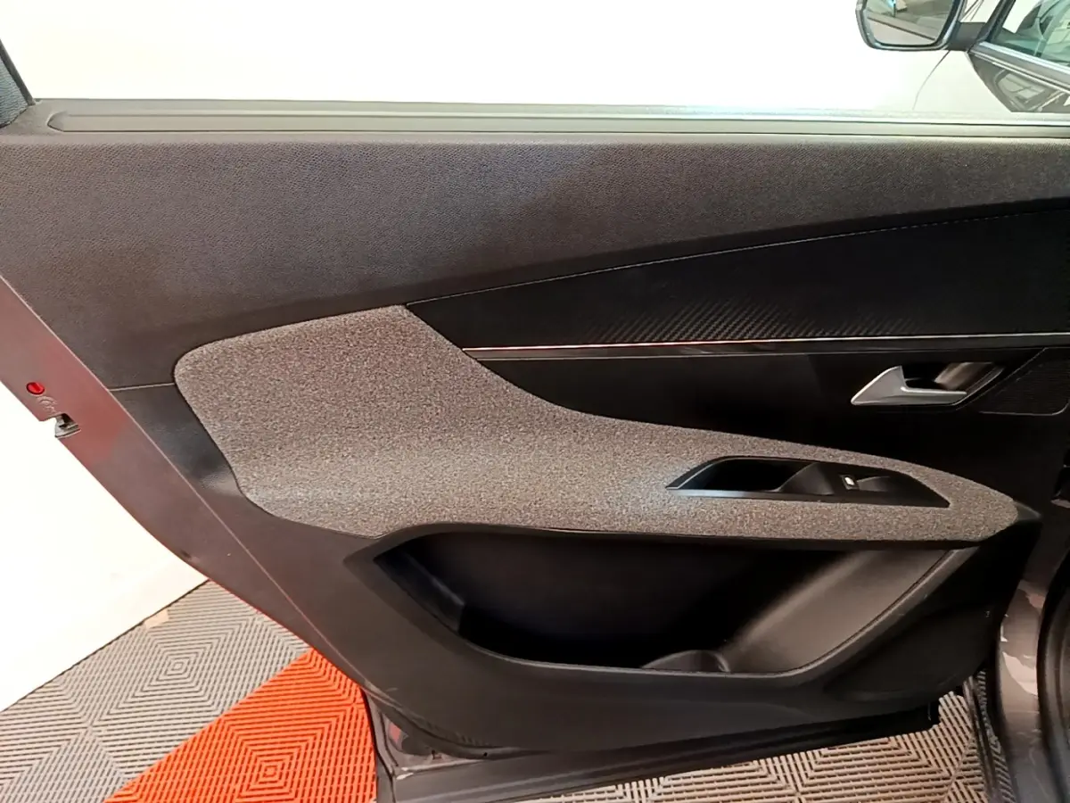 Vue intérieure côté gauche de la porte avant gris clair du Peugeot 5008 avec garniture tissu et plastique noir.