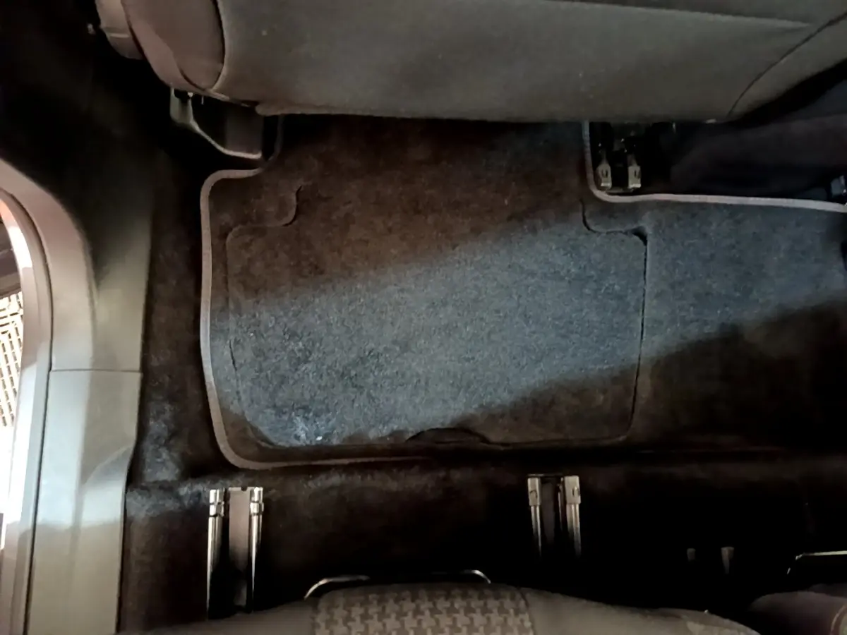 Vue intérieure du plancher arrière du Peugeot 5008 gris clair, montrant les rails des sièges amovibles et la moquette sombre.