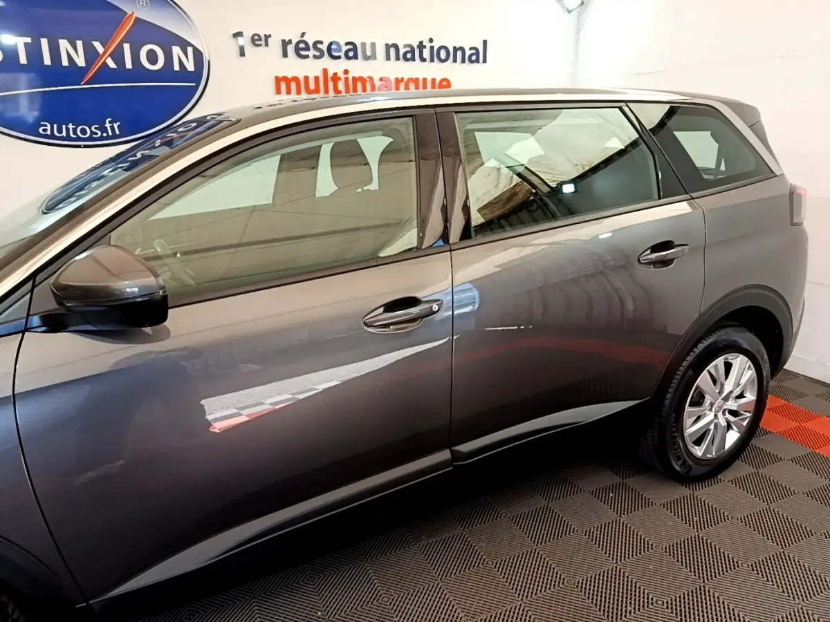 Profil côté gauche d’un Peugeot 5008 gris clair 2021, avec rétroviseurs électriques et jantes alliage visibles.