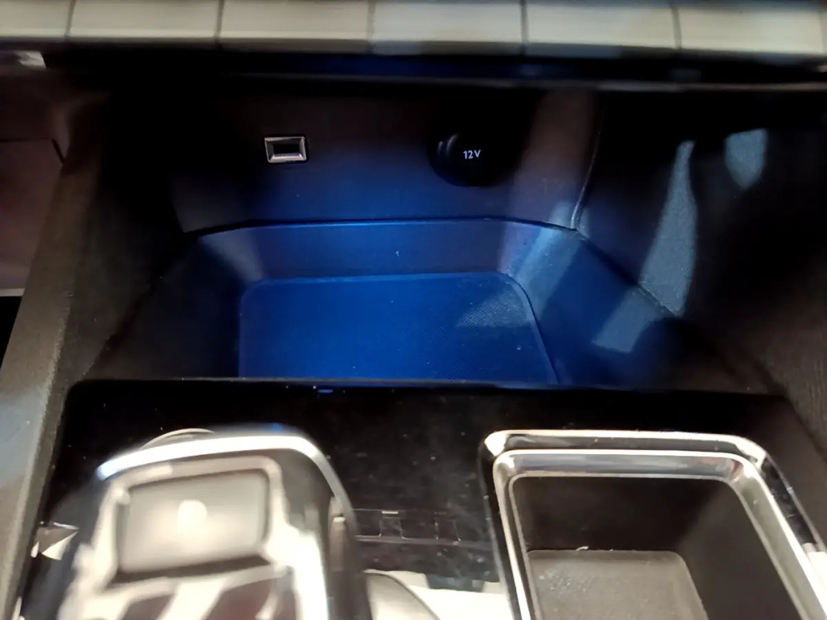 Gros plan sur la console centrale du Peugeot 5008 2021, montrant prise USB, prise 12V et rangement noir brillant.